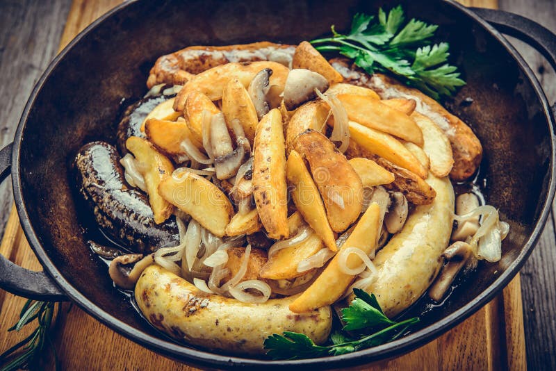 Saucisses frites avec les pommes de terre cuites au four, dans une poêle photographie stock libre de droits Saucisses frites avec les pommes de terre cuites au four, dans une poêle photographie stock libre de droits