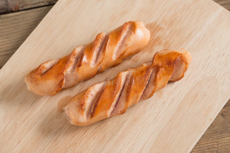 Saucisses grillées sur le conseil en bois photographie stock Saucisses grillées sur le conseil en bois photographie stock