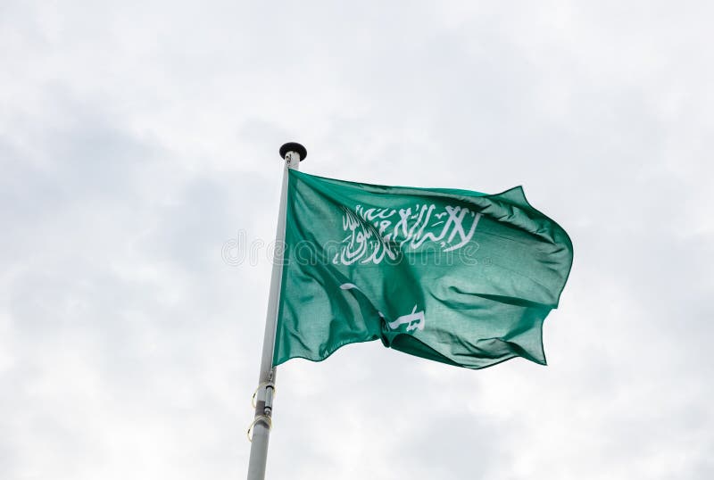 Saudi Arabia flag on a pole waving, cloudy sky background stock images Saudi Arabia flag on a pole waving, cloudy sky background stock images