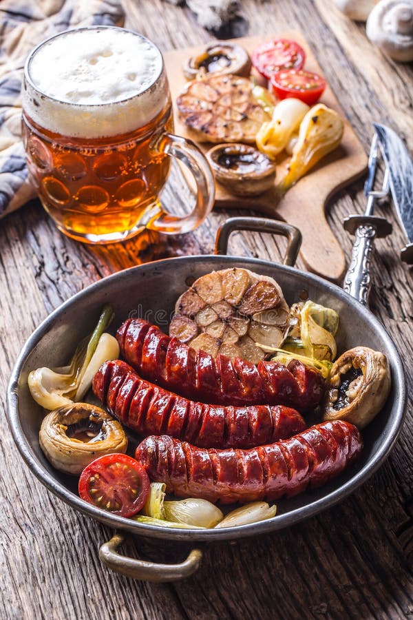 Sausages. Grill sausages. Grilled sausage with beer mushrooms garlic tomatoes and onions stock photos Sausages. Grill sausages. Grilled sausage with beer mushrooms garlic tomatoes and onions stock photos