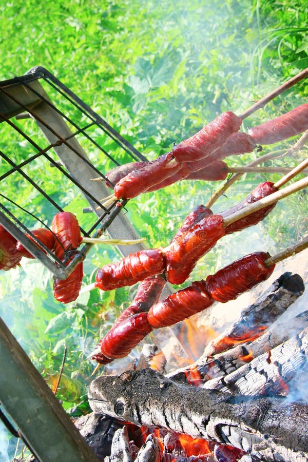 Sausages on sticks held over the campfire