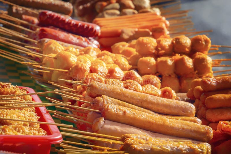 Sausages on wooden skewers, baked on the grill, lie on the table with a traditional Asian street food. Close-up stock images Sausages on wooden skewers, baked on the grill, lie on the table with a traditional Asian street food. Close-up stock images