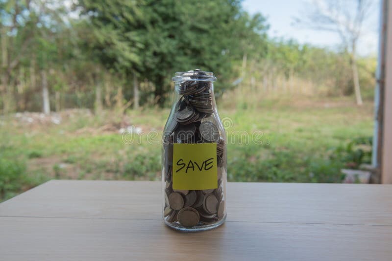 “Save†που γράφει στο έγγραφο, νομίσματα σε ένα βάζο γυαλιού στοκ εικόνα με δικαίωμα ελεύθερης χρήσης