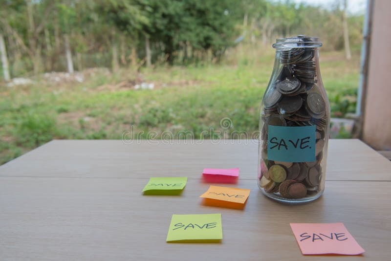 “Save†που γράφει στο έγγραφο, νομίσματα σε ένα βάζο γυαλιού στοκ εικόνες