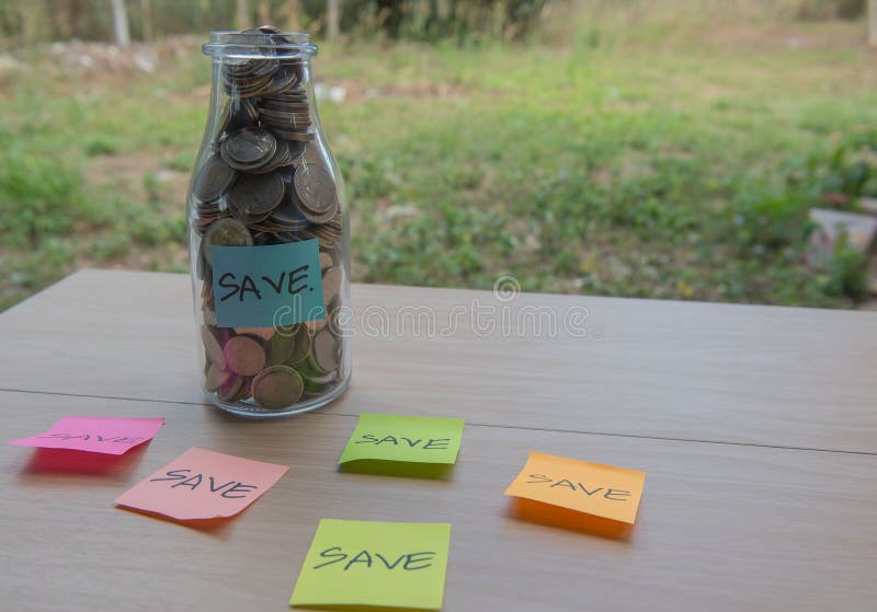 “Save†που γράφει στο έγγραφο, νομίσματα σε ένα βάζο γυαλιού στοκ φωτογραφίες