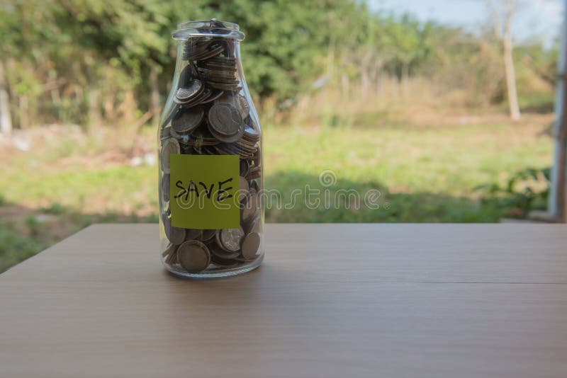 “Save†που γράφει στο έγγραφο, νομίσματα σε ένα βάζο γυαλιού στοκ φωτογραφίες με δικαίωμα ελεύθερης χρήσης