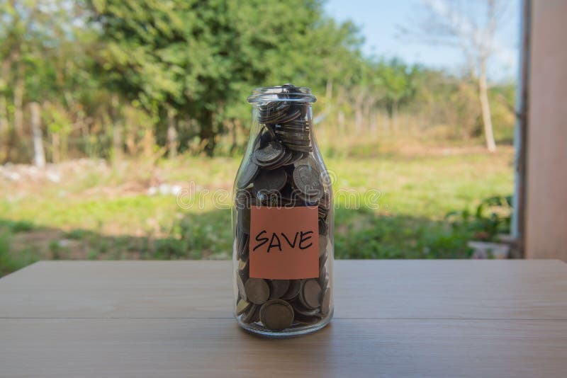 “Save†που γράφει στο έγγραφο, νομίσματα σε ένα βάζο γυαλιού στοκ εικόνα με δικαίωμα ελεύθερης χρήσης