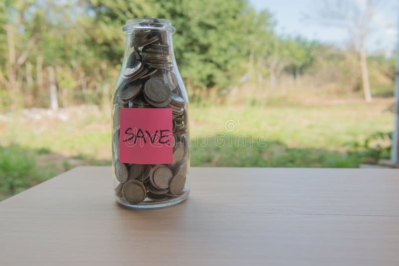 “Save†που γράφει στο έγγραφο, νομίσματα σε ένα βάζο γυαλιού στοκ φωτογραφία με δικαίωμα ελεύθερης χρήσης