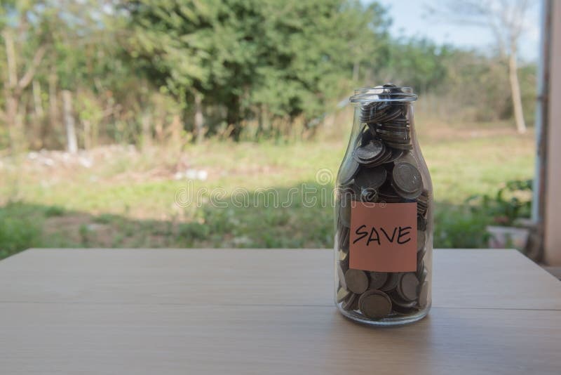 “Save†που γράφει στο έγγραφο, νομίσματα σε ένα βάζο γυαλιού στοκ εικόνα με δικαίωμα ελεύθερης χρήσης