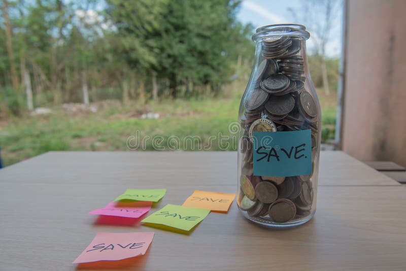 “Save†που γράφει στο έγγραφο, νομίσματα σε ένα βάζο γυαλιού στοκ εικόνα με δικαίωμα ελεύθερης χρήσης