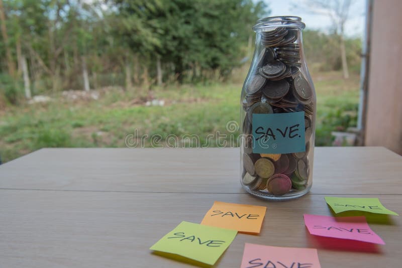 “Save†που γράφει στο έγγραφο, νομίσματα σε ένα βάζο γυαλιού στοκ εικόνες