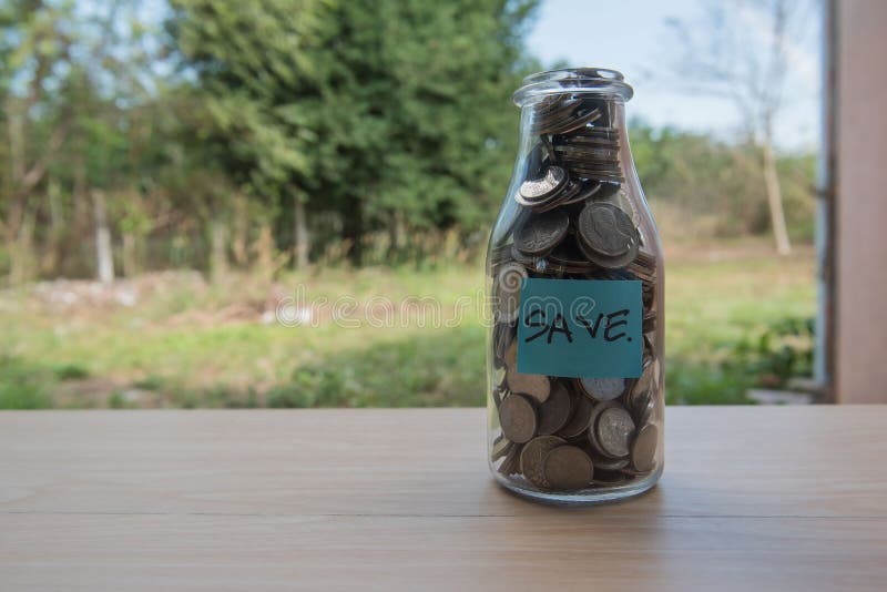 “Save†που γράφει στο έγγραφο, νομίσματα σε ένα βάζο γυαλιού στοκ φωτογραφία με δικαίωμα ελεύθερης χρήσης