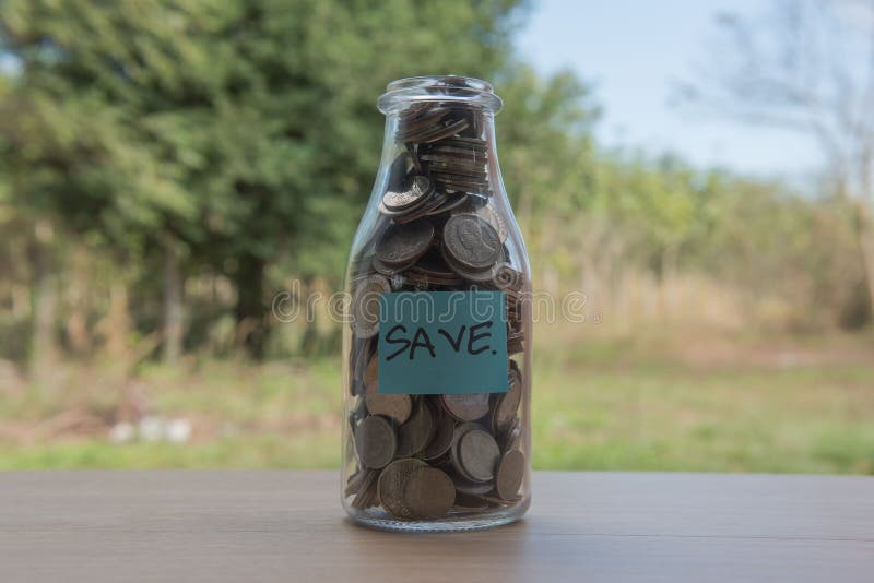“Save†που γράφει στο έγγραφο, νομίσματα σε ένα βάζο γυαλιού, βήμα χρημάτων αποταμίευσης έννοιας με το νόμισμα κατάθεσης στη στοκ φωτογραφίες