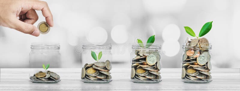 Saving money and investment concepts, Hand putting coin in glass bottles with plants glowing royalty free stock photos