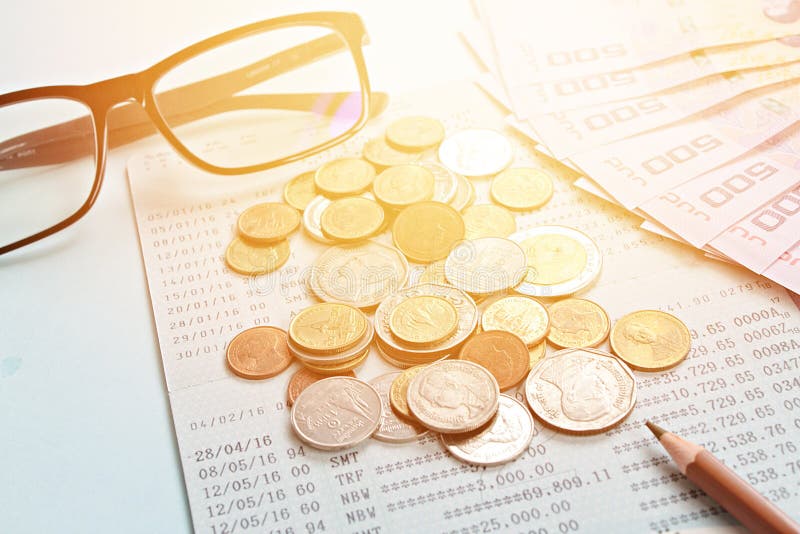 Savings account passbook, Thai money, coins, eye glasses and pencil on blue background royalty free stock photo Savings account passbook, Thai money, coins, eye glasses and pencil on blue background royalty free stock photo