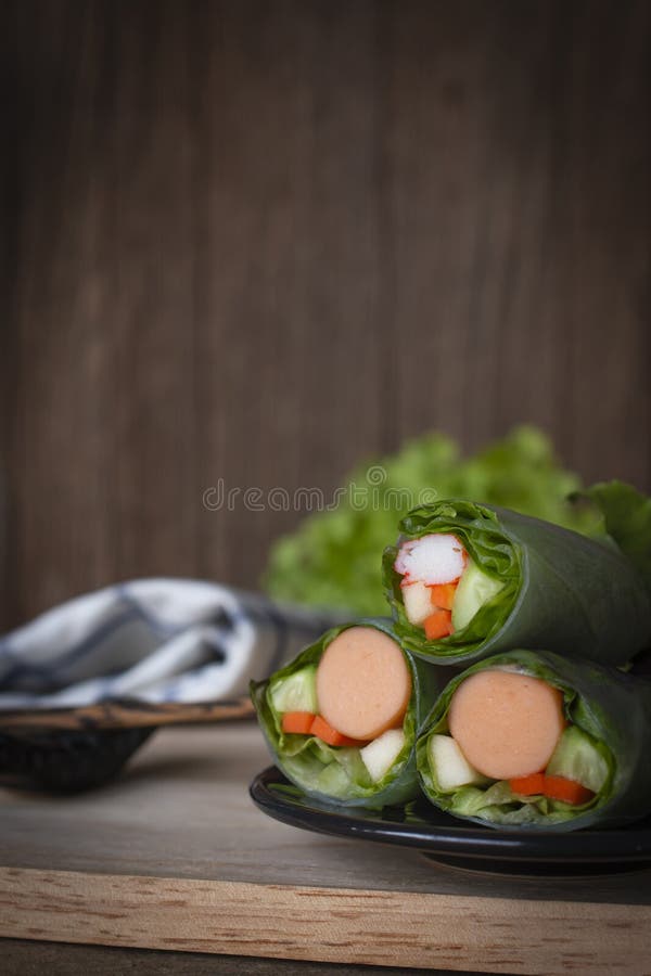 Sałatkowe rolki na czarnym talerzu umieszczającym na drewnie tam są chopsticks, Białym Błękitnym Pasiastym tkaniną i sałata umies zdjęcie royalty free