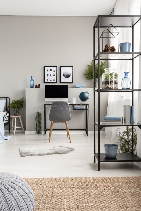 Scaffale del metallo con i coni, i vasi, la pianta ed i libri in Ministero degli Interni scandinavo grigio con lo scrittorio indu fotografia stock Scaffale del metallo con i coni, i vasi, la pianta ed i libri in Ministero degli Interni scandinavo grigio con lo scrittorio indu fotografia stock