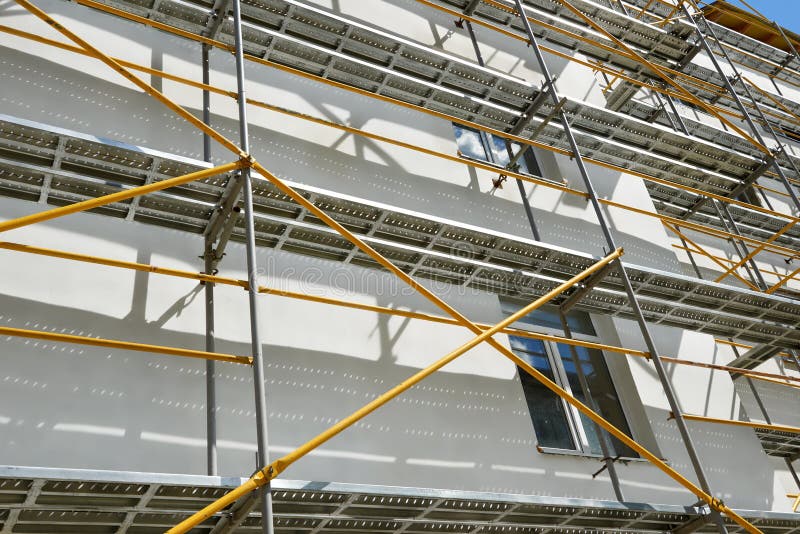 Scaffolding near a house under construction for external plaster works, high apartment building in city, white wall and window, ye. Llow pipe royalty free stock photo Scaffolding near a house under construction for external plaster works, high apartment building in city, white wall and window, ye. Llow pipe royalty free stock photo