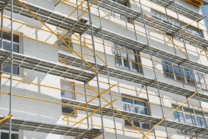 Scaffolding near a new house, building exterior, construction and repair industry, white wall and window, yellow pipe