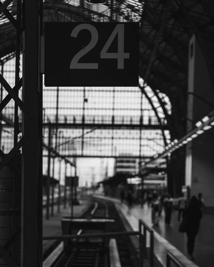 Scala di grigi verticale del numero 24 su uno striscione alla stazione ferroviaria fotografia stock