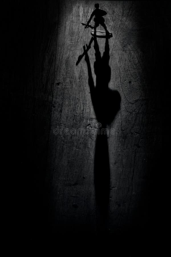 Scala di grigi verticale scattata con un giocattolo con ombra ingrandita immagine stock