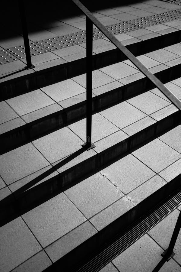 Scala di grigi verticale scatto dalle scale moderne in una strada con ringhiera metallica fotografia stock