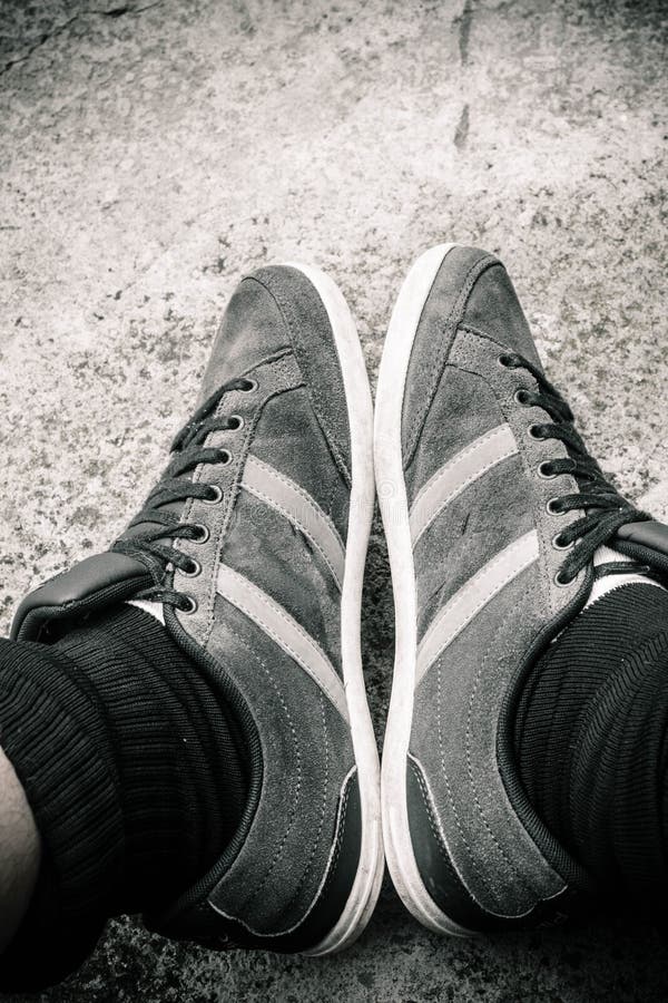 Scala di grigi verticale di un maschio che indossa scarpe da ginnastica a strisce immagini stock libere da diritti