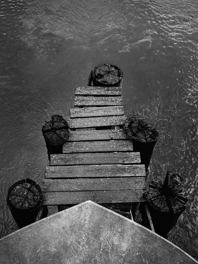 Scala di grigi verticale di un molo di legno fotografia stock