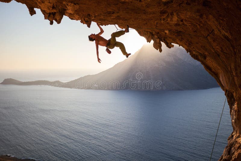 Scalatore che scala lungo il tetto in caverna al tramonto