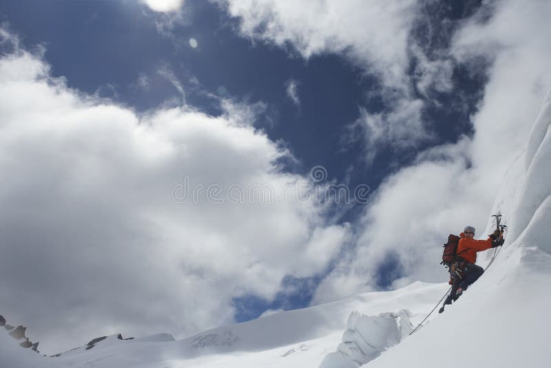 Scalatore di montagna che va su pendio di Snowy con le asce
