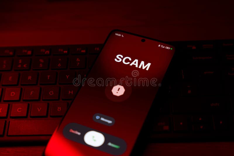 Scam warning on smartphone screen with call options over keyboard, red light stock photography