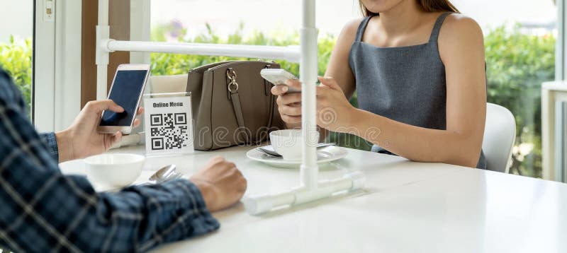 Panoramic Asian customers scan QR code online menu. Customers sat on social distancing table for new normal lifestyle in restaurant after COVID-19 pandemic. Panoramic Asian customers scan QR code online menu. Customers sat on social distancing table for new normal lifestyle in restaurant after COVID-19 pandemic