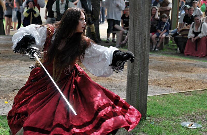 Maiden in traditional costume whirls with a blade at the Scarborough Rennaissance Faire in Waxahachie, Texas. Maiden in traditional costume whirls with a blade at the Scarborough Rennaissance Faire in Waxahachie, Texas.