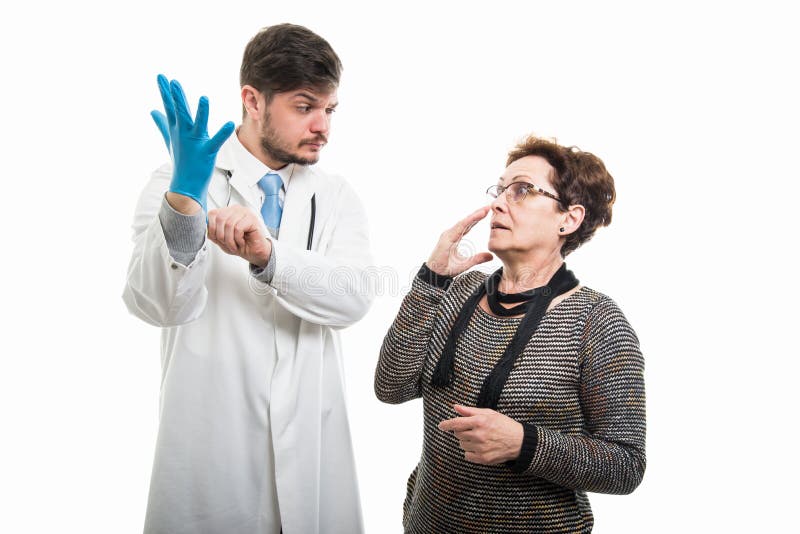 Scared female patient looking to suspicious male doctor with glove royalty free stock images Scared female patient looking to suspicious male doctor with glove royalty free stock images