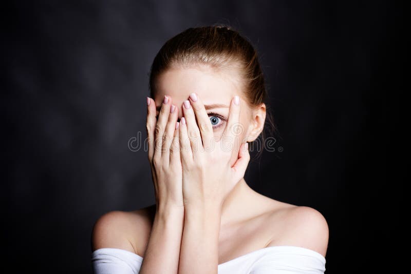 Tight cropped face of a scared young girl with hands covering