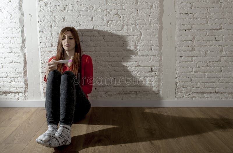 Scared a inquiété la fille enceinte d'adolescent ou la jeune femme désespérée tenant l'essai de grossesse positif images libres de droits Scared a inquiété la fille enceinte d'adolescent ou la jeune femme désespérée tenant l'essai de grossesse positif images libres de droits