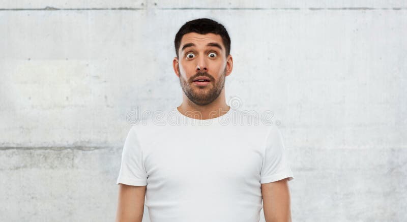 Scared man in white t-shirt over wall background