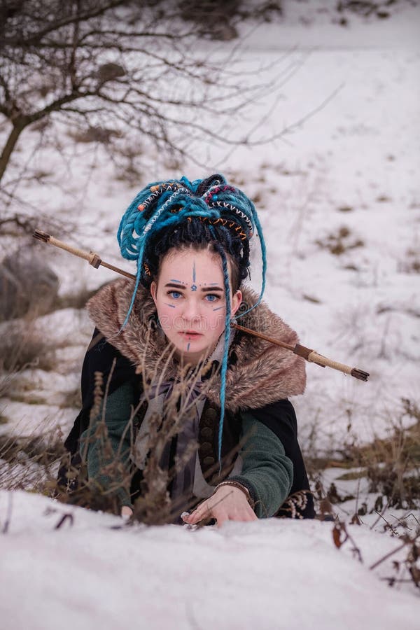 Scared Viking woman with a sword in a black long mantle with fur. portrait of a dreamy girl. female with blue hair dreadlocks royalty free stock photography Scared Viking woman with a sword in a black long mantle with fur. portrait of a dreamy girl. female with blue hair dreadlocks royalty free stock photography