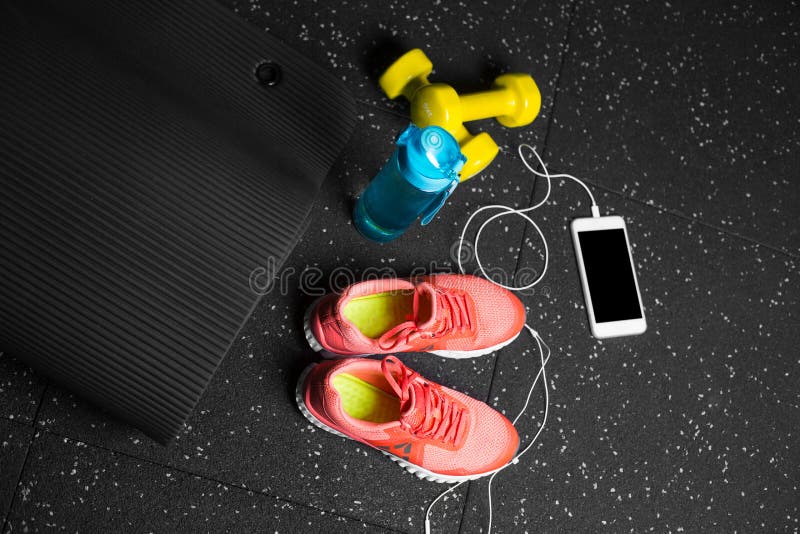 Scarpe comode di sport, una bottiglia di acqua, teste di legno e telefono su un fondo nero Accessori per addestramento della pale immagini stock Scarpe comode di sport, una bottiglia di acqua, teste di legno e telefono su un fondo nero Accessori per addestramento della pale immagini stock