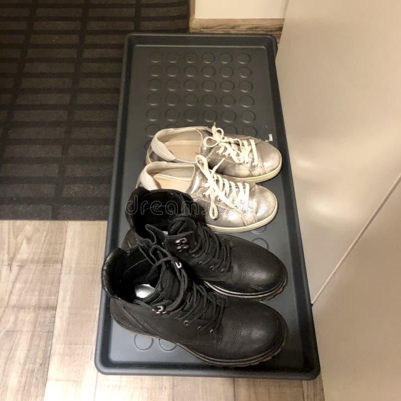 scarpe da ginnastica e stivali si trovano su un vassoio per scarpe nel corridoio