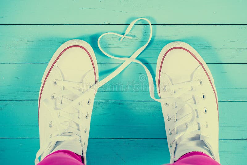 White sneakers with heart on blue wood background, filtered image. White sneakers with heart on blue wood background, filtered image