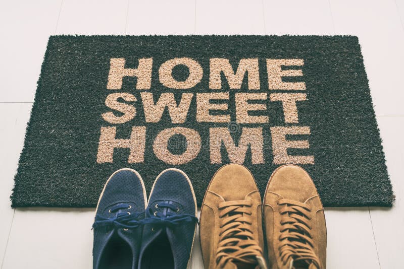 Scarpe di tappetino all'ingresso principale dell'appartamento di condo Un cartello scritto di benvenuto a casa dolce casa, che dà