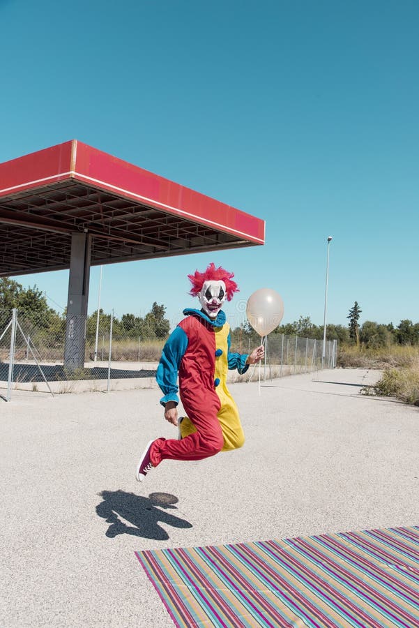 Scary clown with a golden balloon outdoors royalty free stock images Scary clown with a golden balloon outdoors royalty free stock images