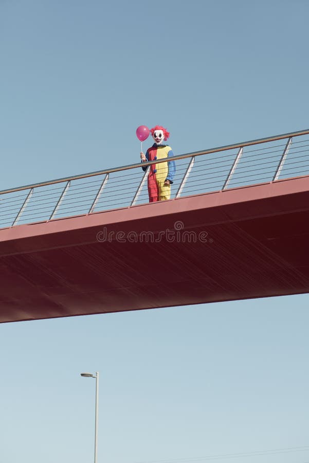 Scary clown with a red balloon on a bridge royalty free stock photos Scary clown with a red balloon on a bridge royalty free stock photos
