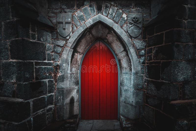 Scary pointy red wooden door in an old and wet stone wall building with cross, skull and bones at both sides. Concept mystery, death and danger