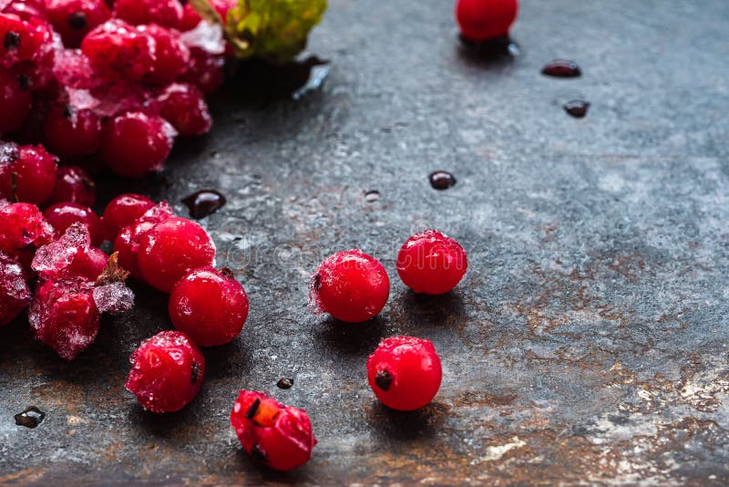 Scattered frozen red currants closeup lie on a rusty surface. copy space. horizontal royalty free stock photos