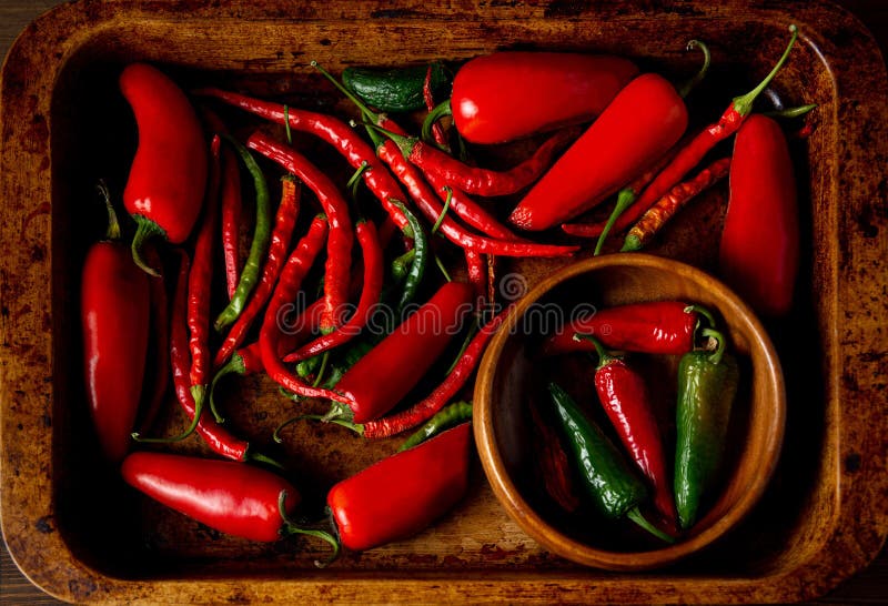 A scattering bunch of red chilies and green Romano peppers on a wooden tray. Colorful juicy hot peppers. Shot from above royalty free stock image A scattering bunch of red chilies and green Romano peppers on a wooden tray. Colorful juicy hot peppers. Shot from above royalty free stock image
