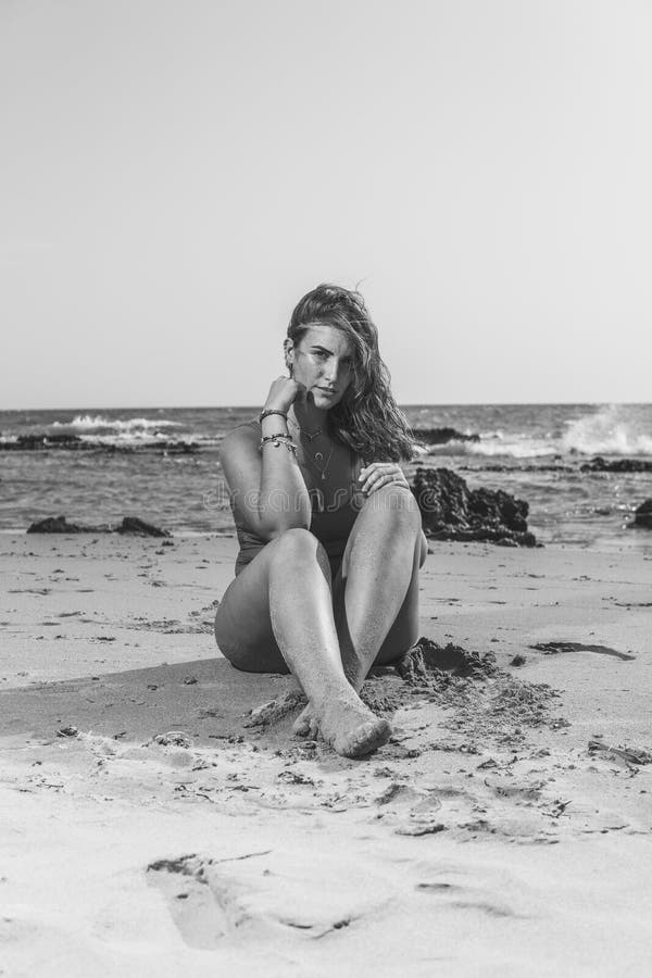 Scatto in scala di grigi verticale di una bellissima donna europea con costume da bagno sulla spiaggia di sandy fotografie stock libere da diritti
