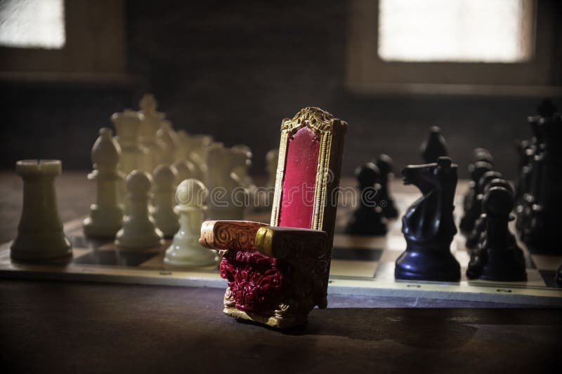 Scaun regal roșu în miniatură pe masă din lemn. Tronul Medieval pe tabla de șah. Conceptul de joc de șah la bord al ideilor de afa stock image