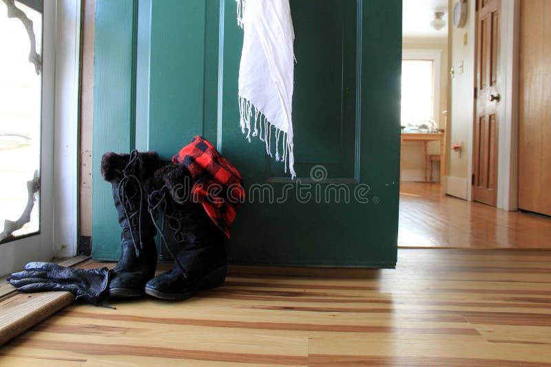 Scena d'invito con gli stivali di inverno delle signore, la sciarpa dei guanti ed il cappello vicino alla porta aperta della casa fotografie stock libere da diritti Scena d'invito con gli stivali di inverno delle signore, la sciarpa dei guanti ed il cappello vicino alla porta aperta della casa fotografie stock libere da diritti